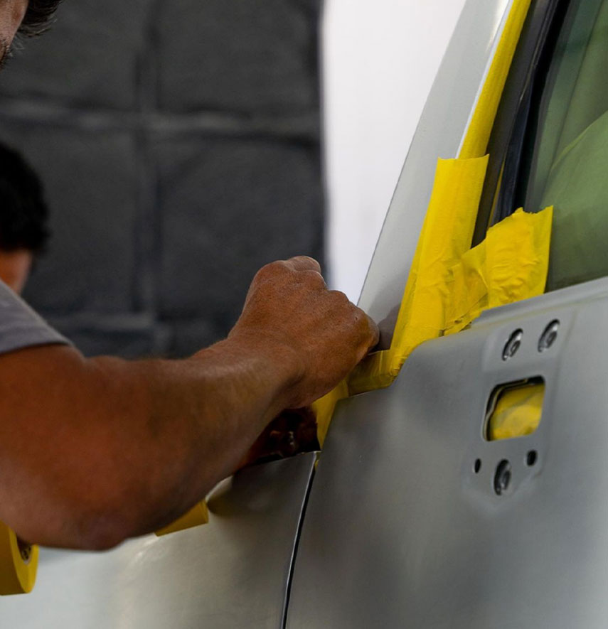 Image of a body shop technician taping auto body panels