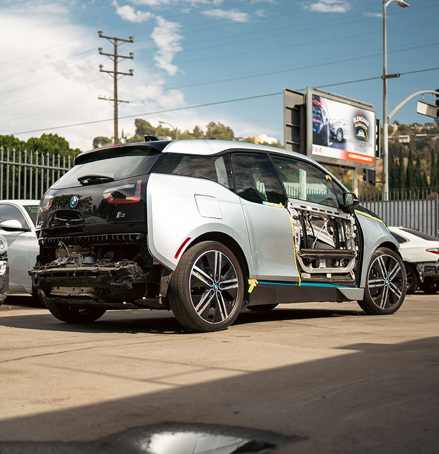 Image of a BMW i3 with a missing door panel at the shop for auto body repairs