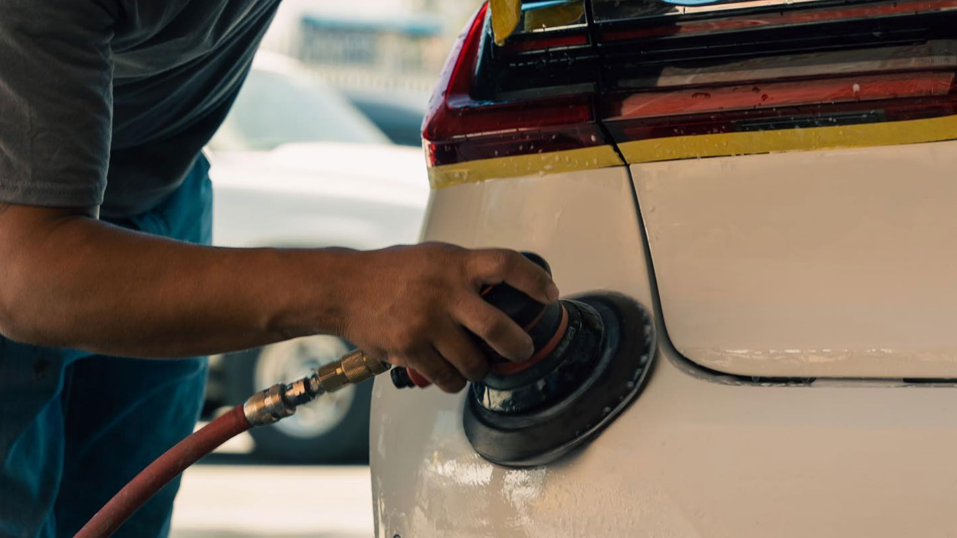 An image of an auto body tech sanding a vehicle and prepping for paint work